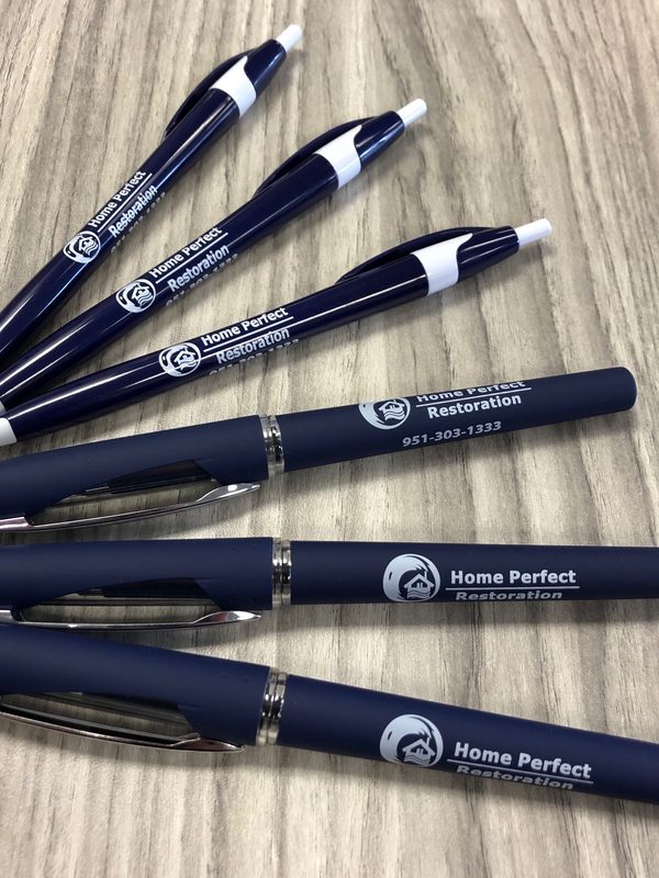 Navy blue pens printed with the Home Perfect Restoration logo and phone number